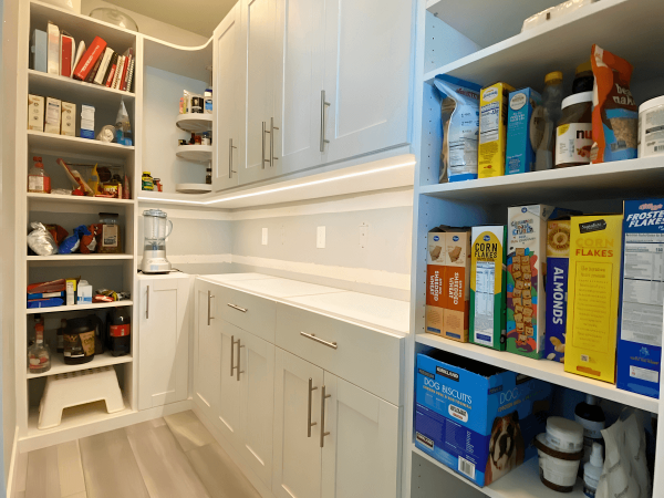 Custom pantry showing cabinets, and shelves with cook books, food and storage.