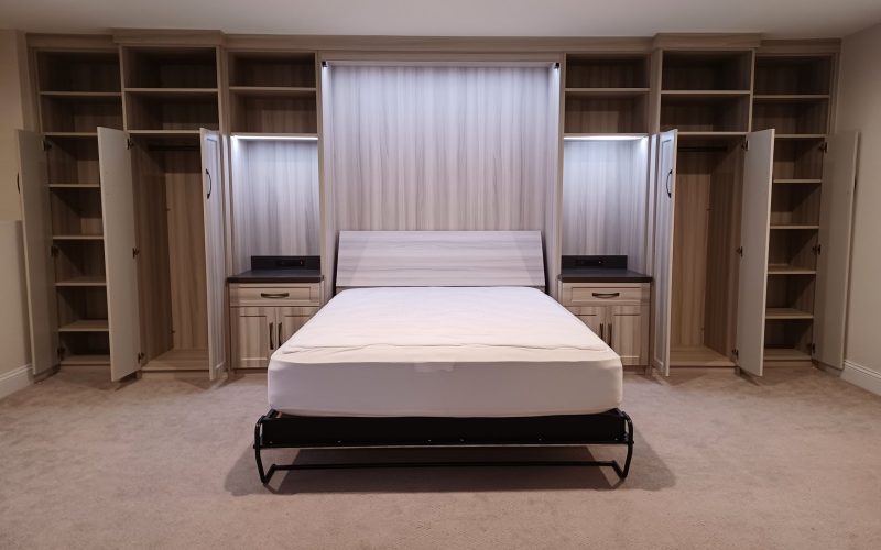 Wall Bed open in room with custom cabinets doors open showing storage space.